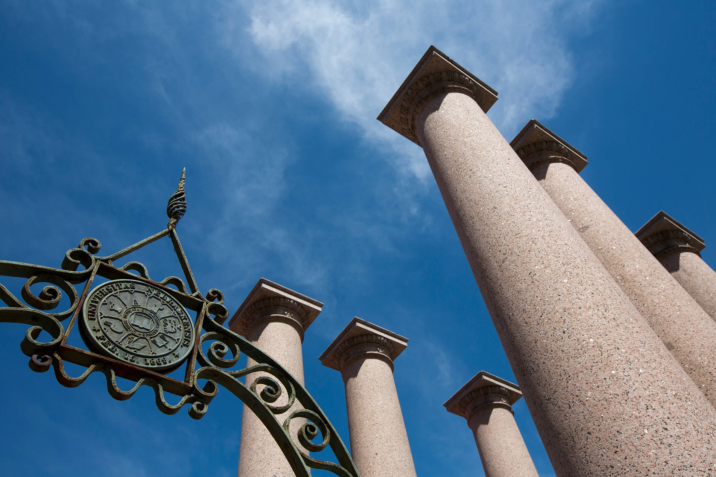 Columns and metal University seal in front of blue sky