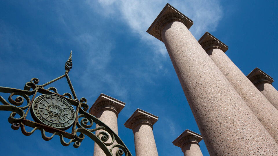 Columns and metal University seal in front of blue sky